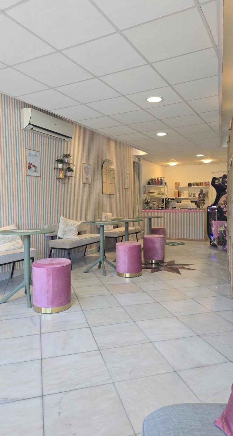 Salon De Thé Bondues Intérieur d'un café avec des tables et des tabourets roses, atmosphère chaleureuse.