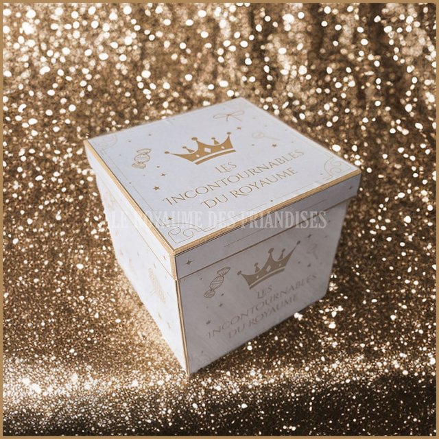 Box Cadeau "Les Incontournables" Bondues Boîte blanche ornée d'une couronne, posée sur un fond scintillant doré.