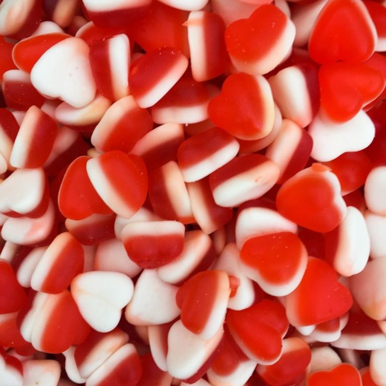 Bonbons Bondues Bonbons en forme de cœurs rouges et blancs, dispersés sur une surface.