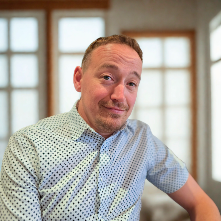 Jérome DAMART - Bondues Homme souriant portant une chemise à motifs, assis dans un intérieur lumineux.