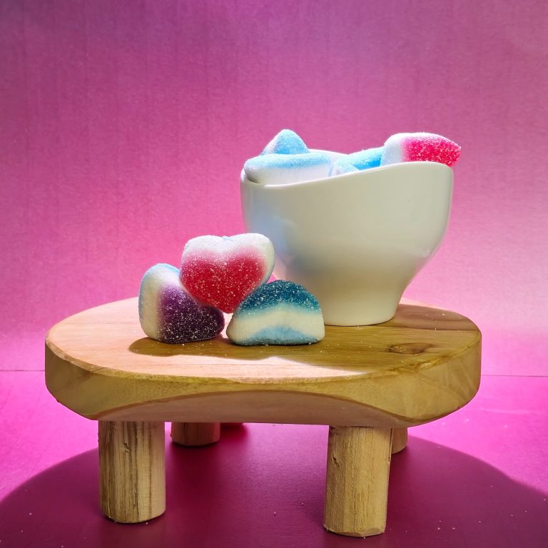 Bonbons Bondues Bonbons colorés en forme de cœur, présentés dans un bol sur une table en bois.